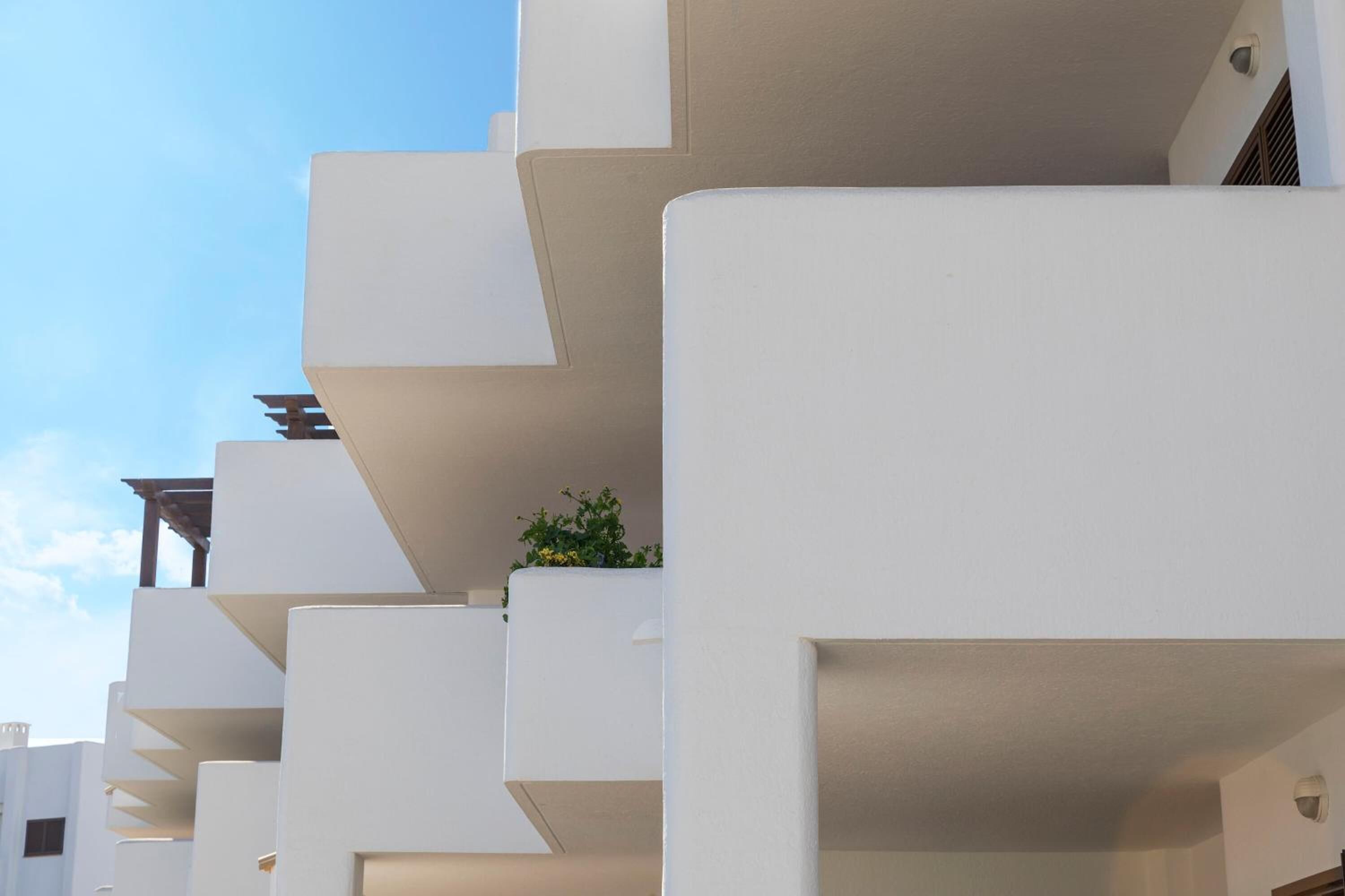 A modern building with white balconies and a clear sky.