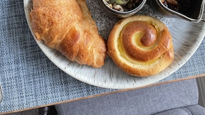 A breakfast plate with a croissant, a cinnamon roll, a bowl of mixed berries, yogurt, and a small bowl of nuts. - Beck Allans Guesthouse (Ambleside)