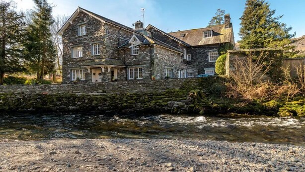 A stone building with multiple windows and a stone wall in front. - Beck Allans Guesthouse (Ambleside)