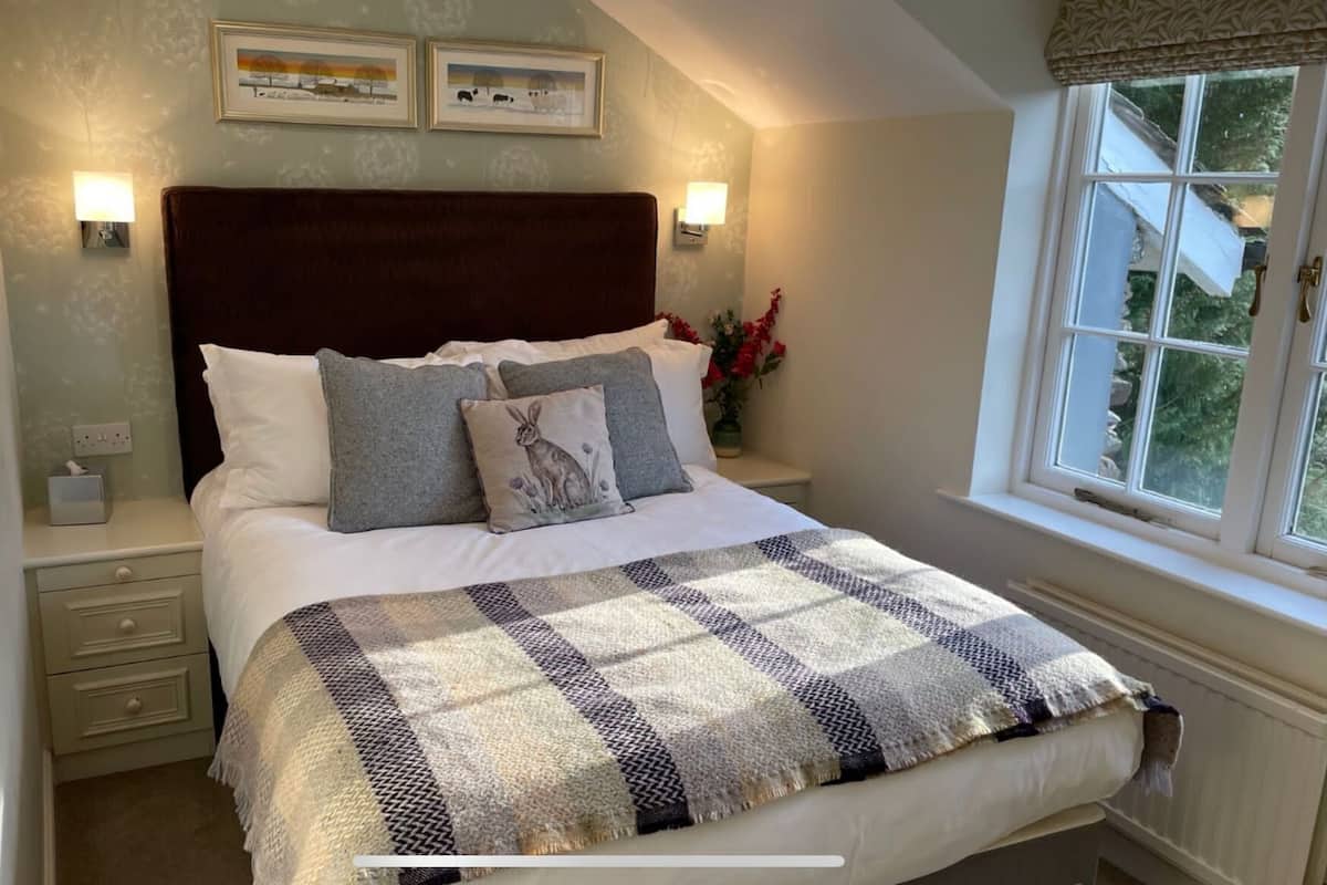 A neatly made bed with a checkered blanket, a dark headboard, and two bedside lamps.