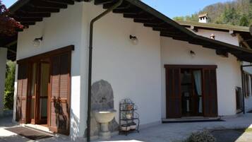 Una casa moderna con facciata in pietra, persiane in legno e un vaso in pietra.