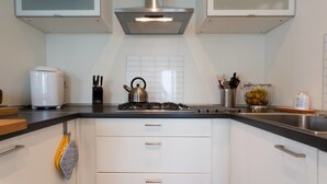 A modern kitchen with white cabinets, a stainless steel range hood, a kettle, and a fruit bowl. - Contemporary 3 Bed Italian Lakes Villa, Lake Views, Wifi, BBQ (Massino Visconti)