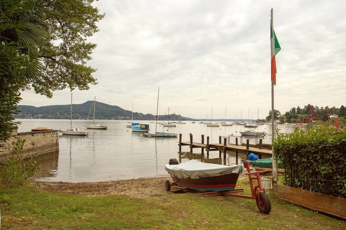 A marina with several boats docked, a flagpole with a flag, and a grassy area with a cart.
