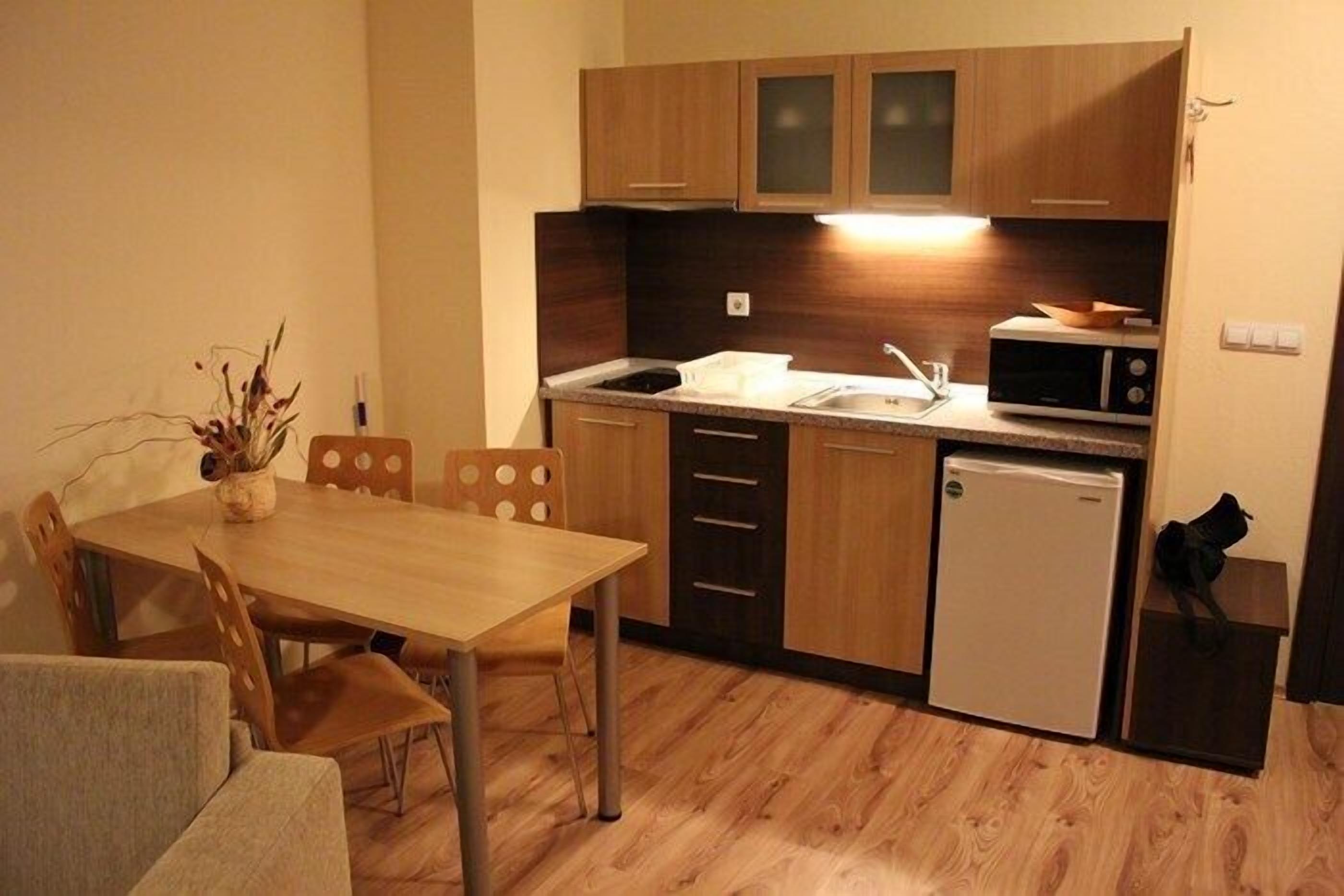 A compact kitchen with wooden cabinets, a microwave, a sink, and a small refrigerator.