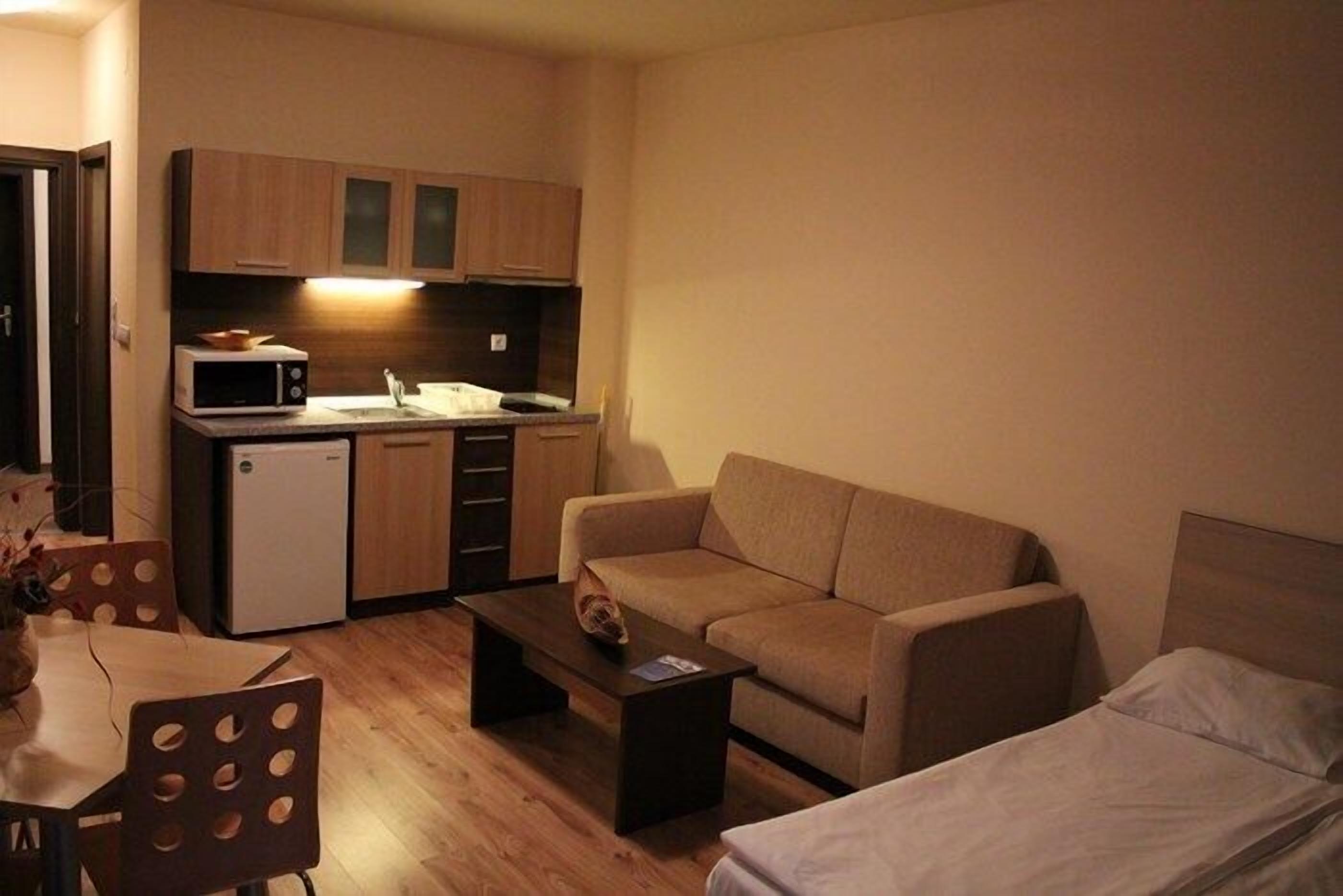 Un espace de vie compact comprenant un coin cuisine, un canapé, une petite table et un lit.