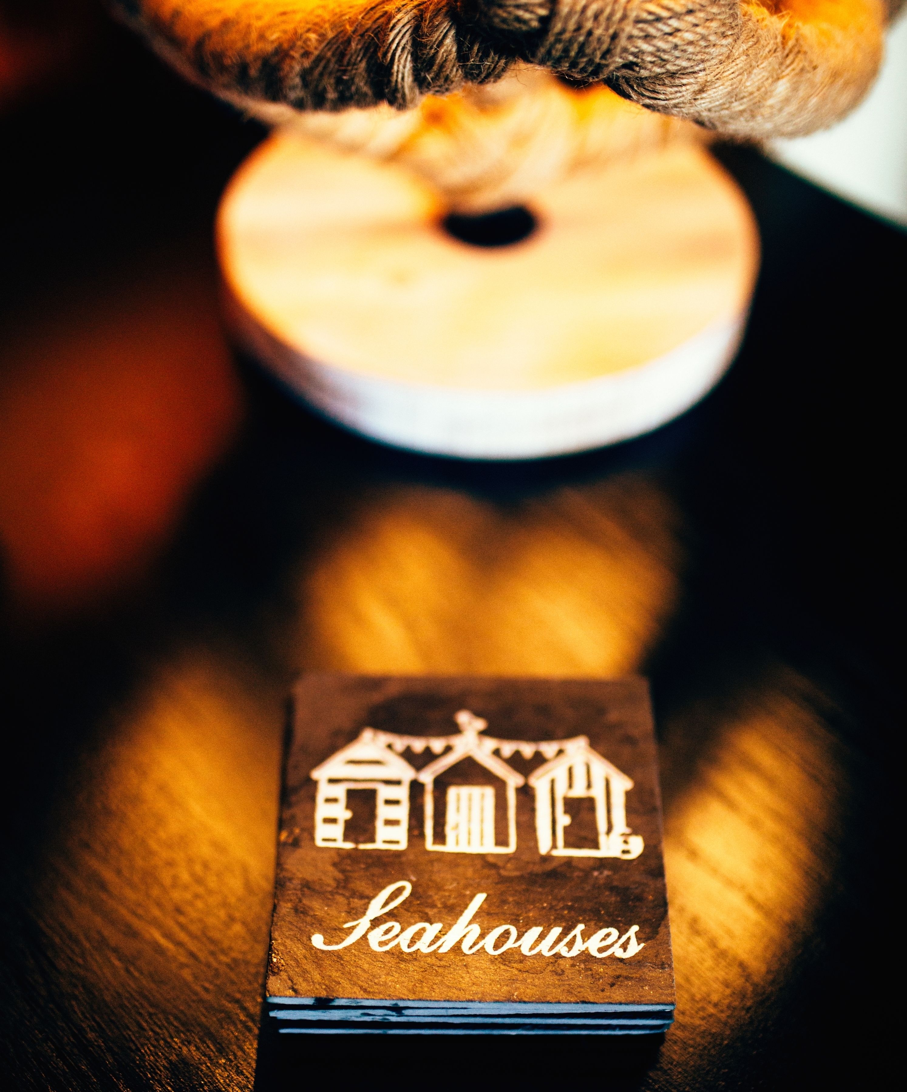 A wooden block with a house design and the text "Seahouses" on a dark surface.