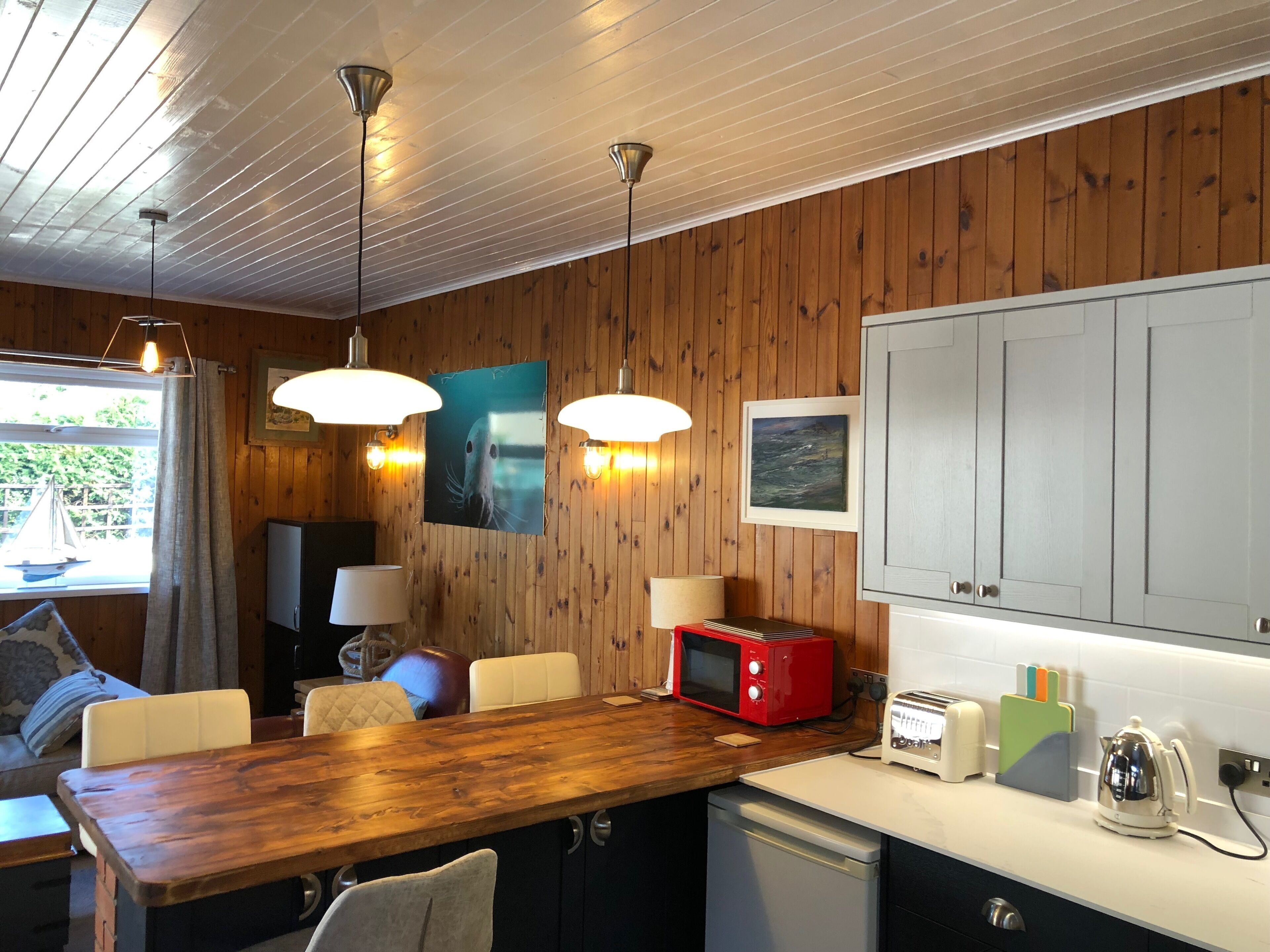 A cozy kitchen with wooden walls, a wooden dining table, and modern appliances.