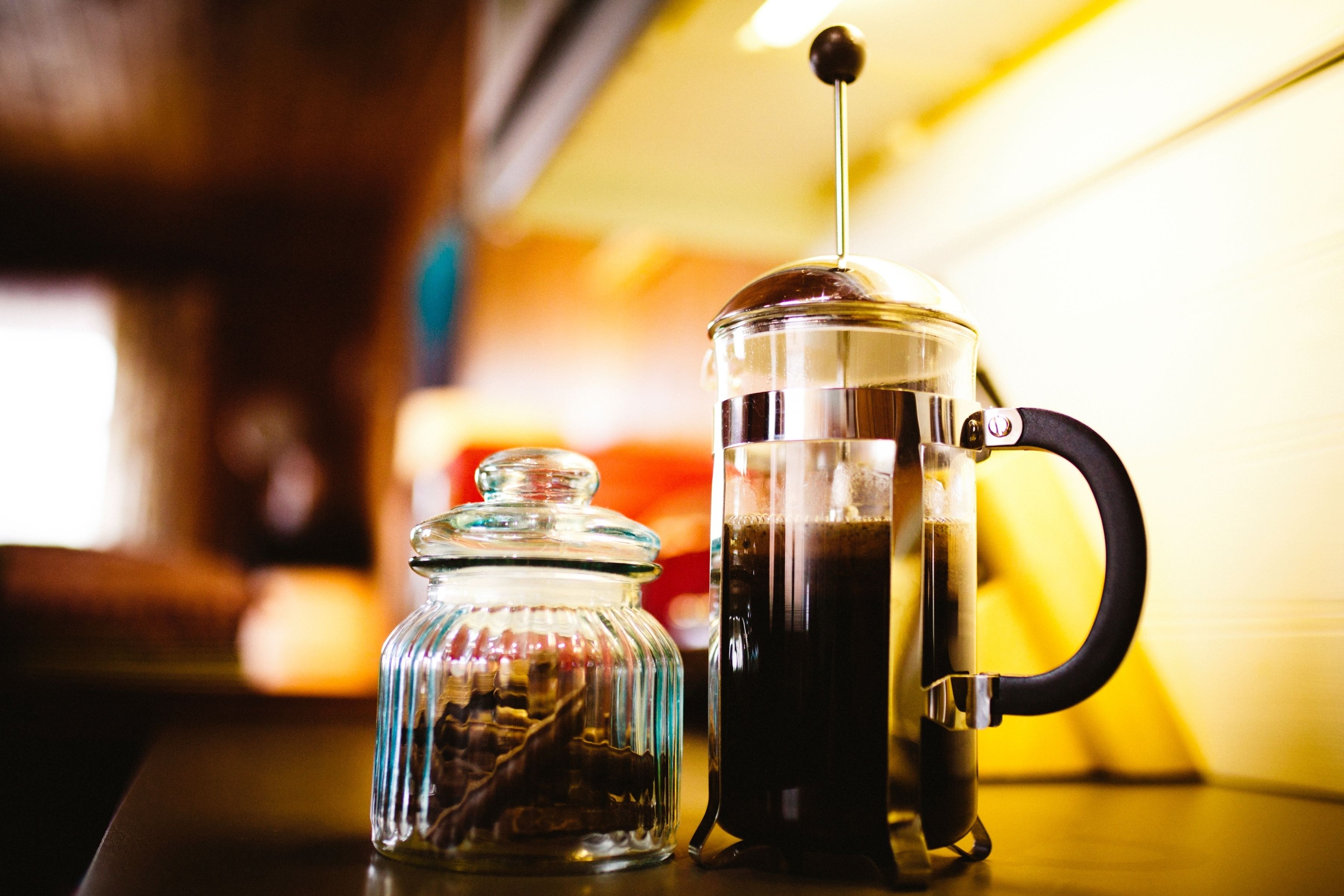 A coffee maker and a glass jar on a table.