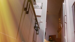 A staircase with a handrail, a door, and a ceiling light fixture. - Coalminer's Cottage (Gateshead)