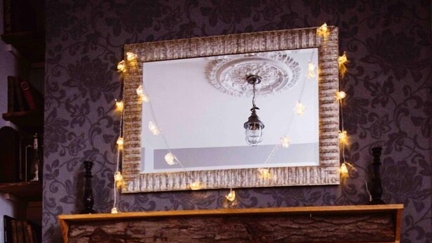A fireplace with a mantel, a television on a stand, and a patterned wallpaper. - Coalminer's Cottage (Gateshead)