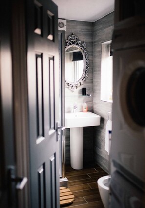A bathroom with a modern design, featuring a white sink, a large mirror, and a toilet. - Coalminer's Cottage (Gateshead)