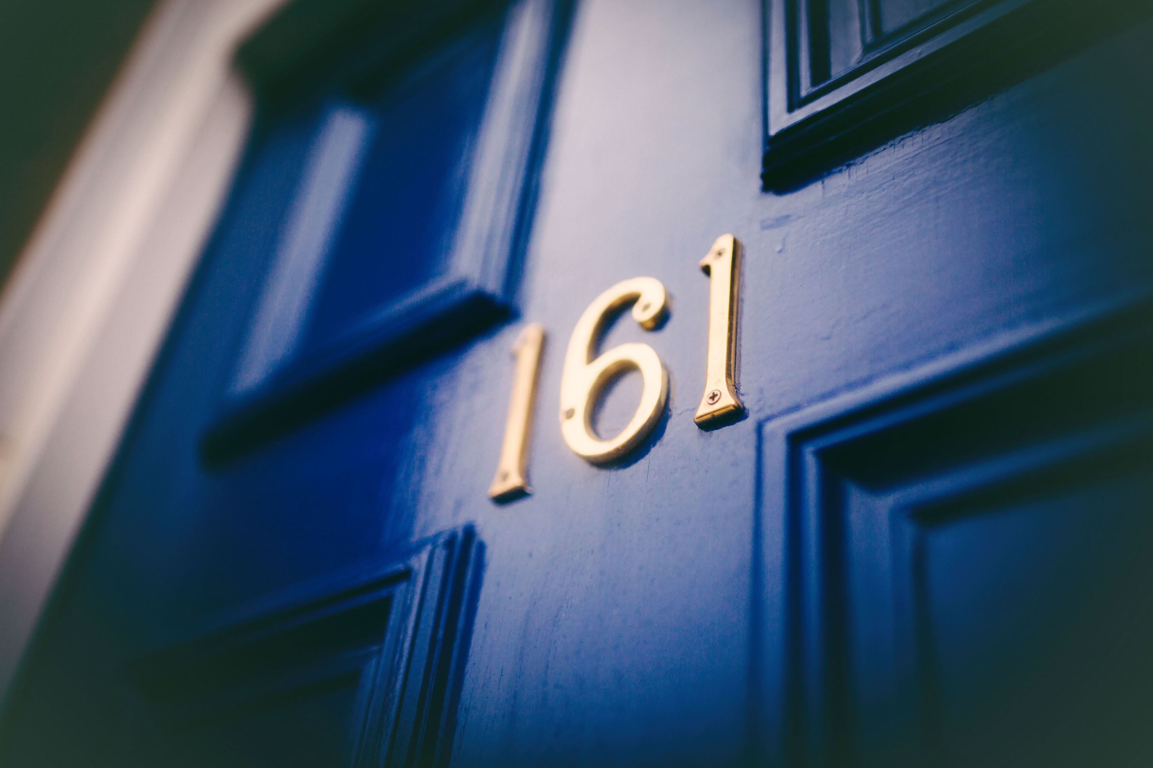 A close-up of a blue door with the number 161 in gold lettering.