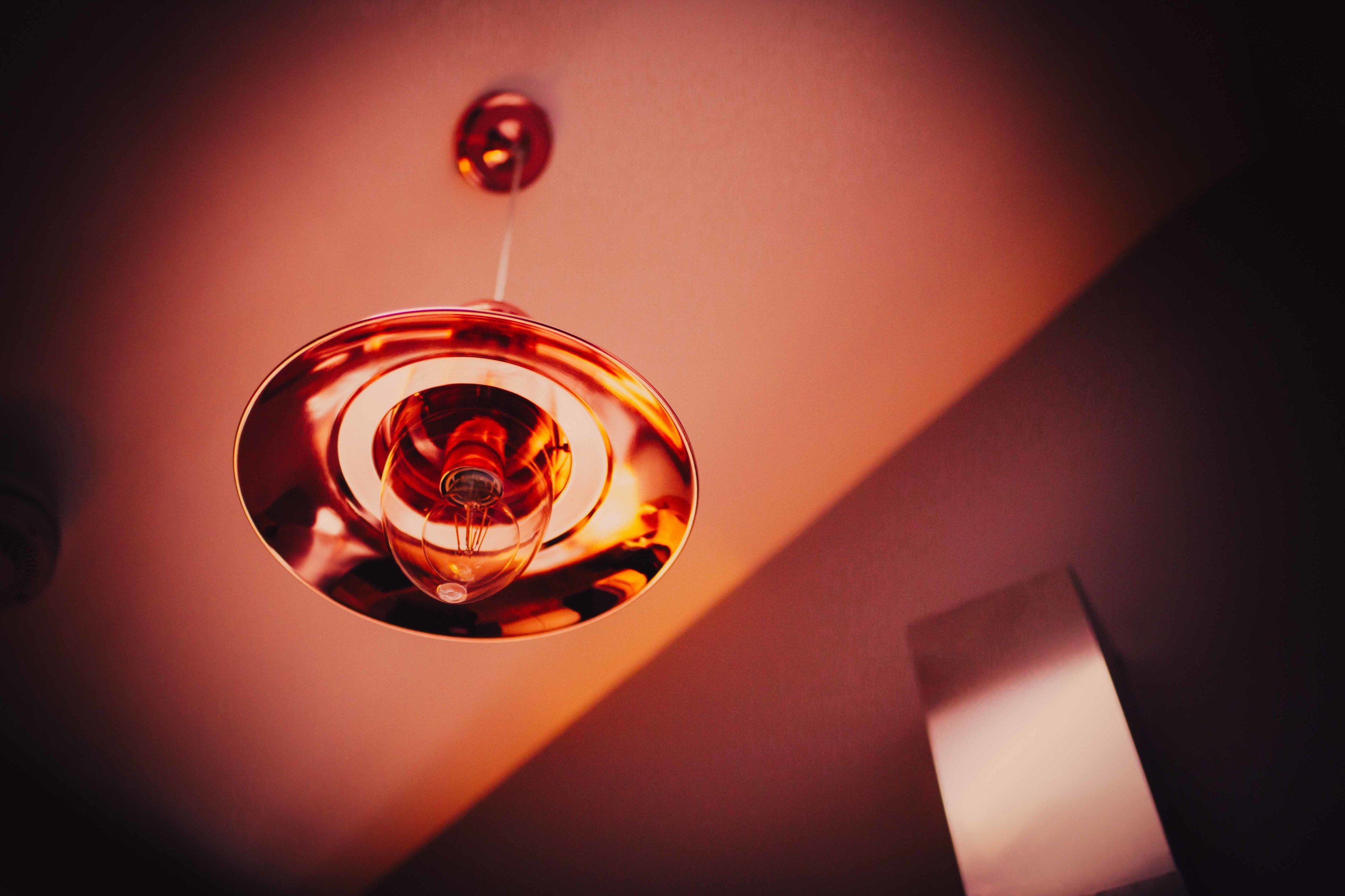 A pendant light fixture with a reflective surface and a visible bulb.