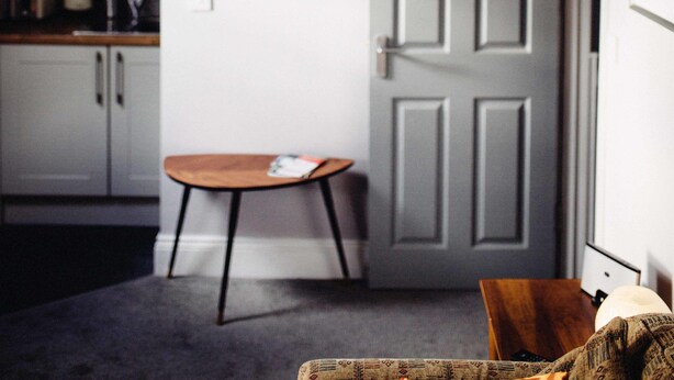 Une pièce avec un plafond en pente, une table en bois, une porte et un tableau encadré au mur.