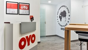 Zona de recepción con un mostrador, sillas y una pared con un mapa del mundo y texto.