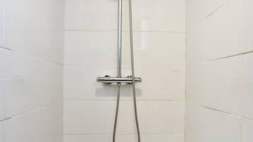 Een douche met een handdouche en een vaste douchekop in een betegelde badkamer.