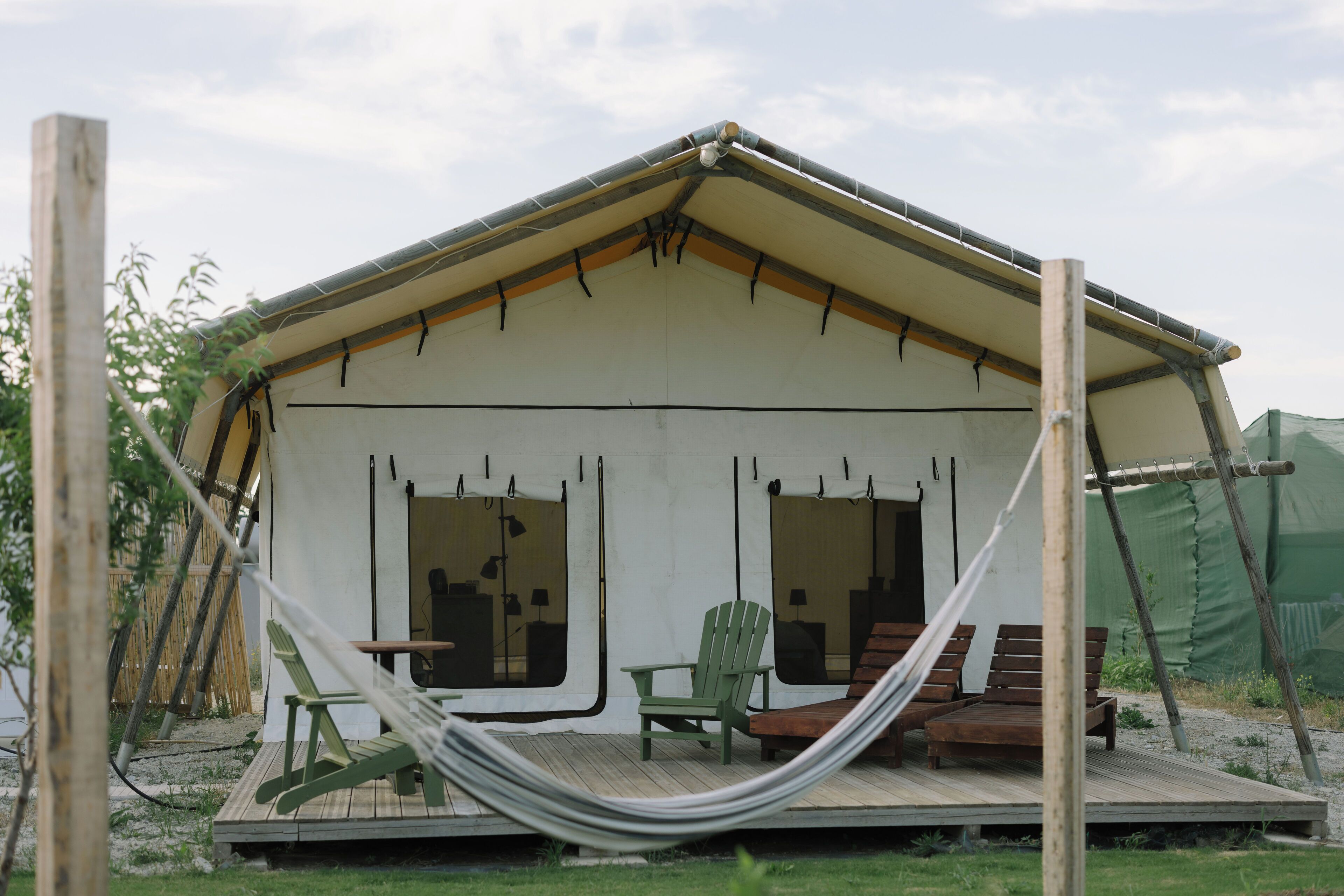 A small, single-story building with a porch, a hammock, and a green chair.