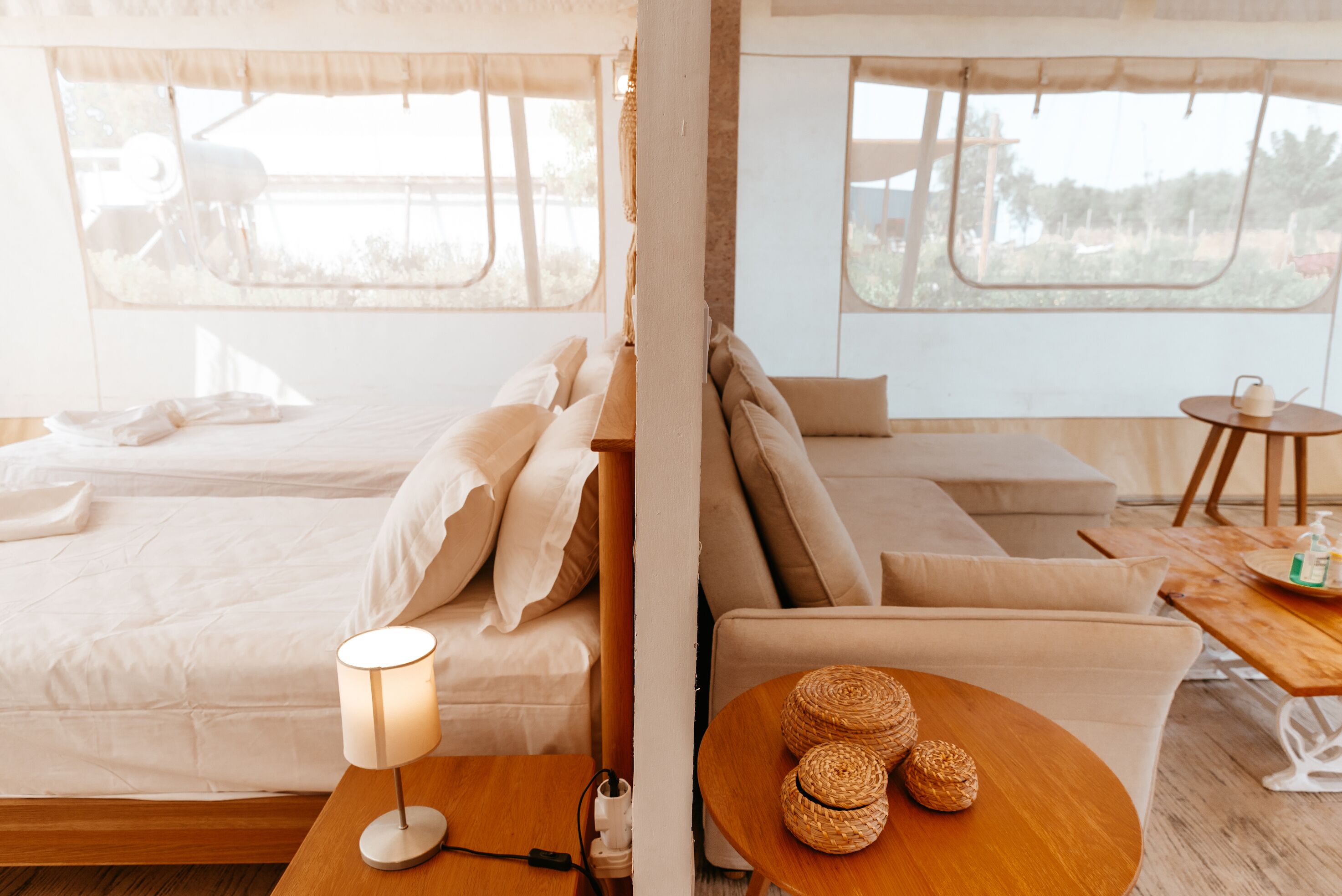 A cozy room with a bed, a sofa, a table with woven baskets, and a lamp.
