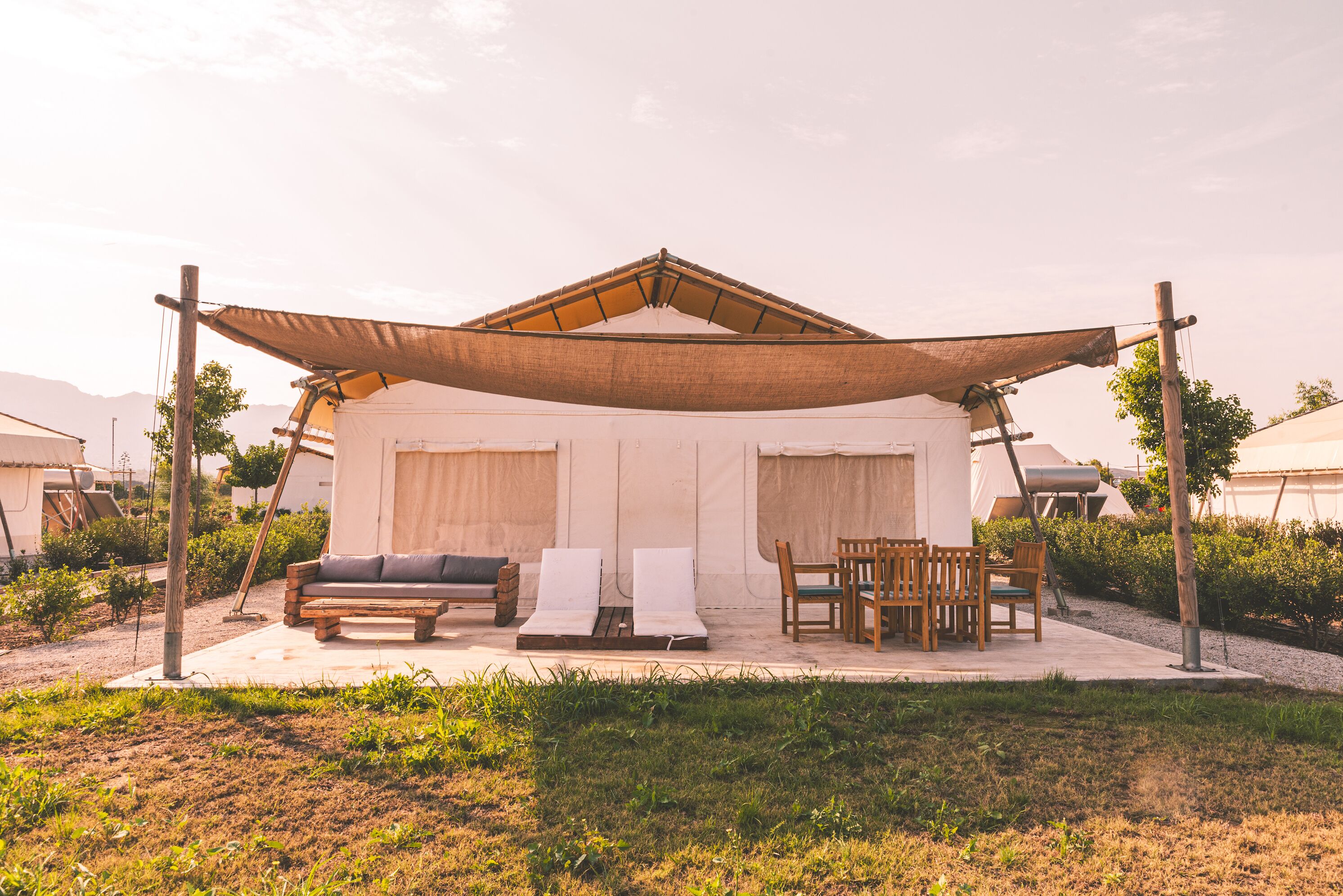 Un espacio de estar al aire libre techado con un banco, sillones de lounge y una mesa.