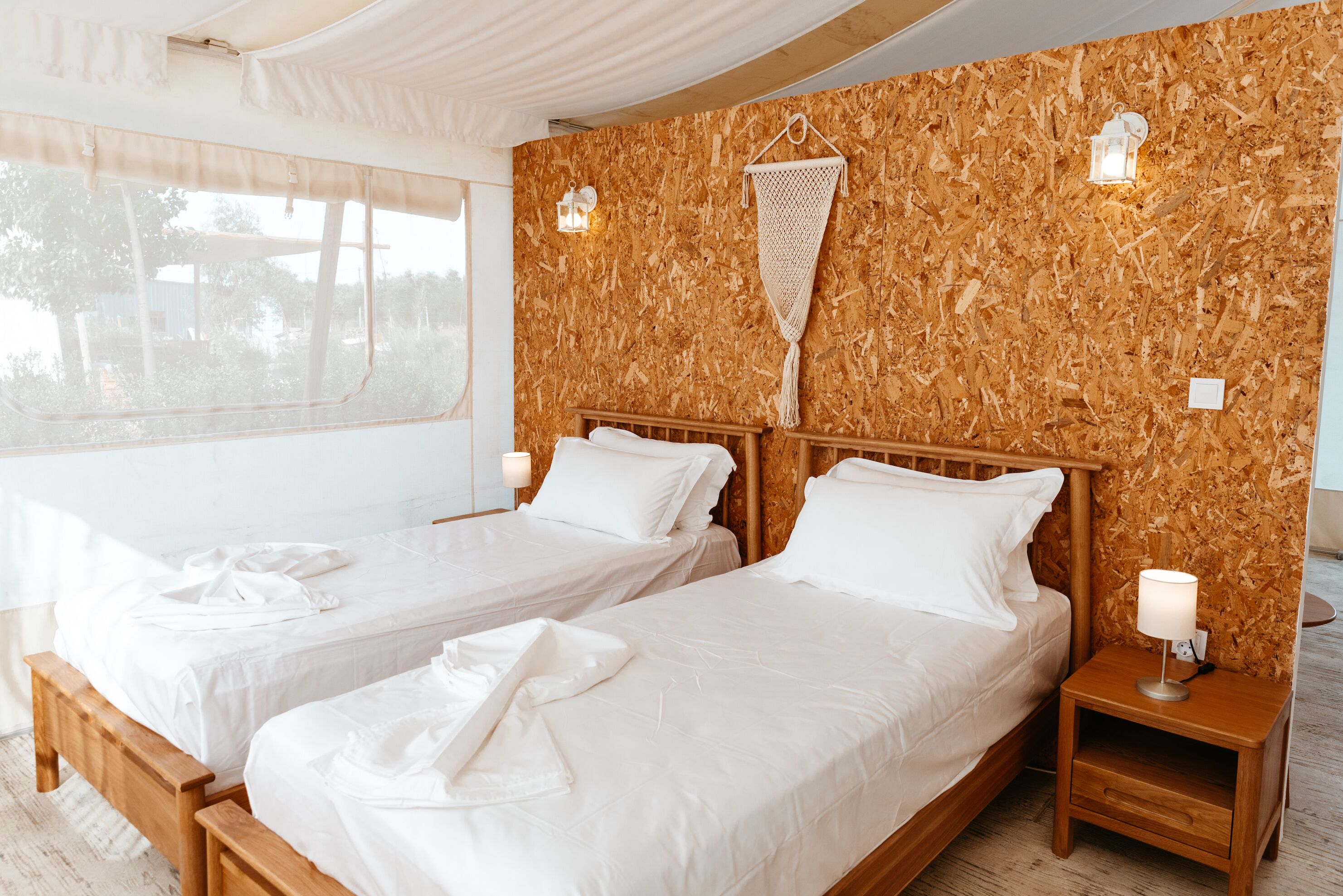 A room with two beds, wooden headboards, and a wooden wall.