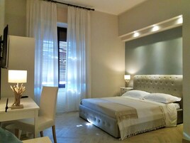 Una camera d'albergo con un letto grande, una scrivania con una lampada e una sedia.