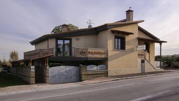 A two-story building with a flat roof, a balcony, and a garage entrance.