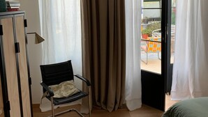 A room with a bed, a chair, a wardrobe, and a view through a door to an outdoor area. - Casa Lourido (Sada)
