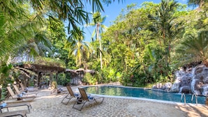 A pool area with lounge chairs and a waterfall backdrop. - Ylang Ylang Beach Resort (Cóbano)