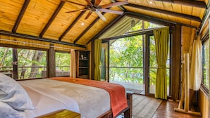 Un dormitorio amplio con una cama grande, techo de madera y vistas al exterior.