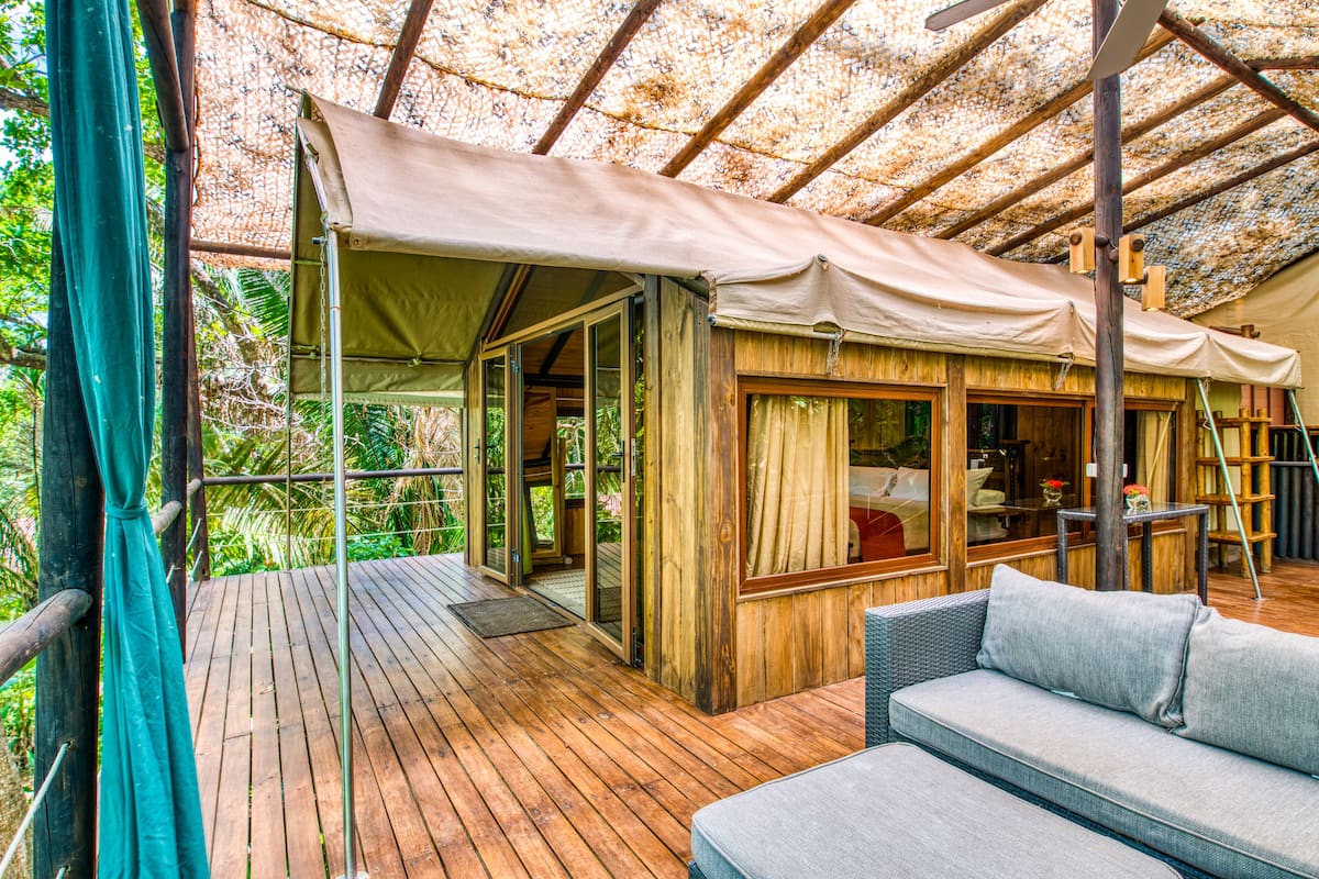 A wooden deck with a covered seating area and a glass door leading to an interior space.