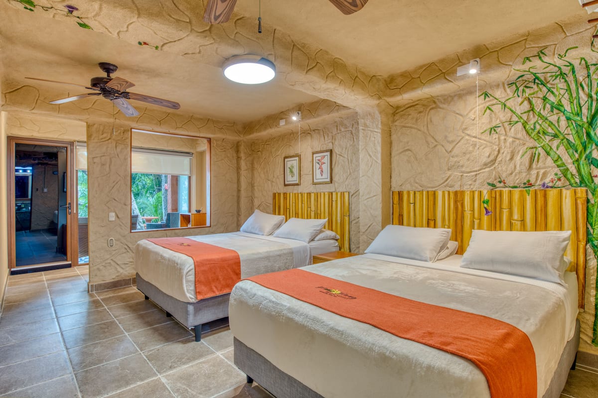 A hotel room with two beds, a ceiling fan, and a large window.