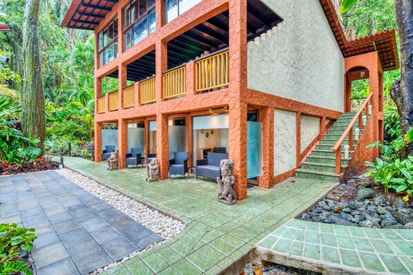 A two-story building with a stone facade, outdoor seating area, and a staircase leading to the upper level. - Ylang Ylang Beach Resort (Cóbano)