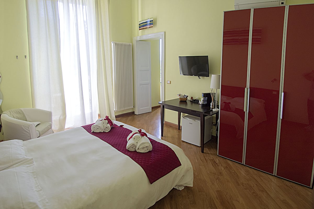 A hotel room with a bed, a desk, a television, and a wardrobe.