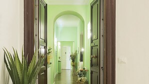 Un pasillo con una puerta verde, un felpudo con el texto 'RESIDENCY' y una planta a la izquierda.