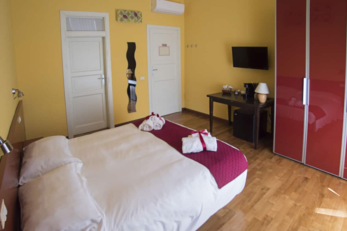 A hotel room with a bed, a desk, a TV, and a wardrobe.