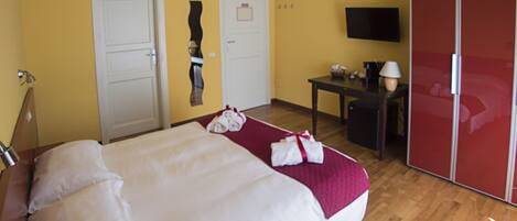 A hotel room with a bed, a desk, a TV, and a wardrobe.