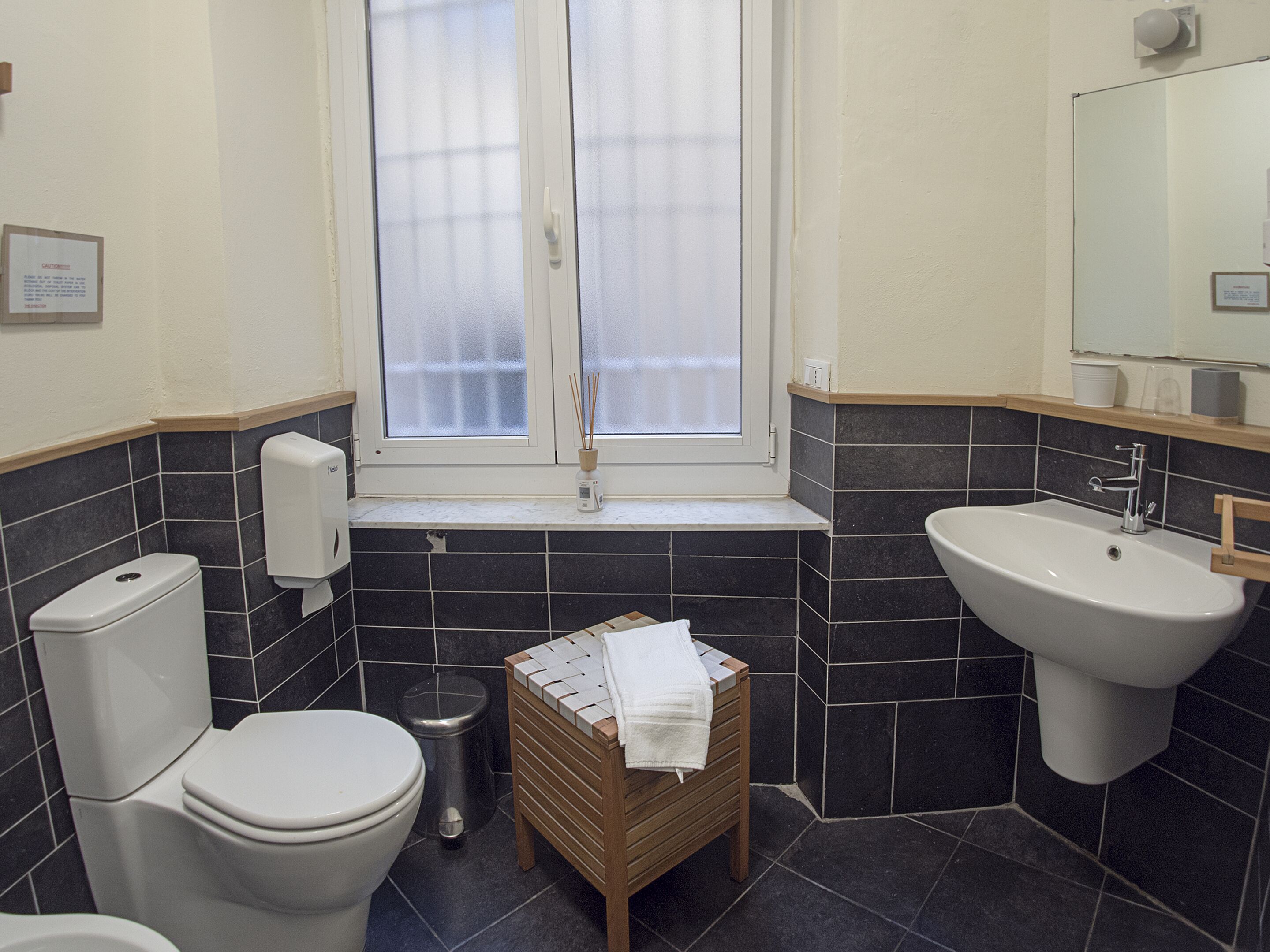 Un bagno con toilette, bidet, lavandino e finestra con vetro satinato.