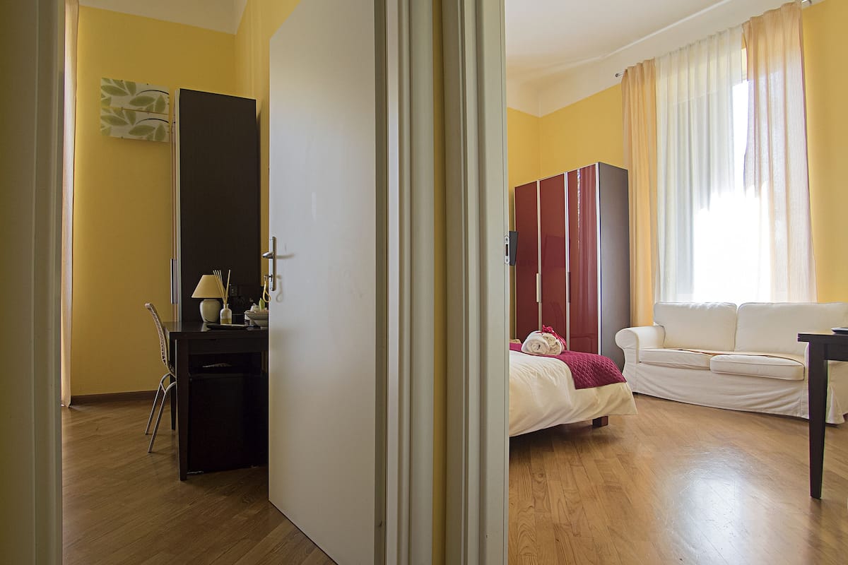 A hotel room with a bed, a desk, a wardrobe, and a sofa.
