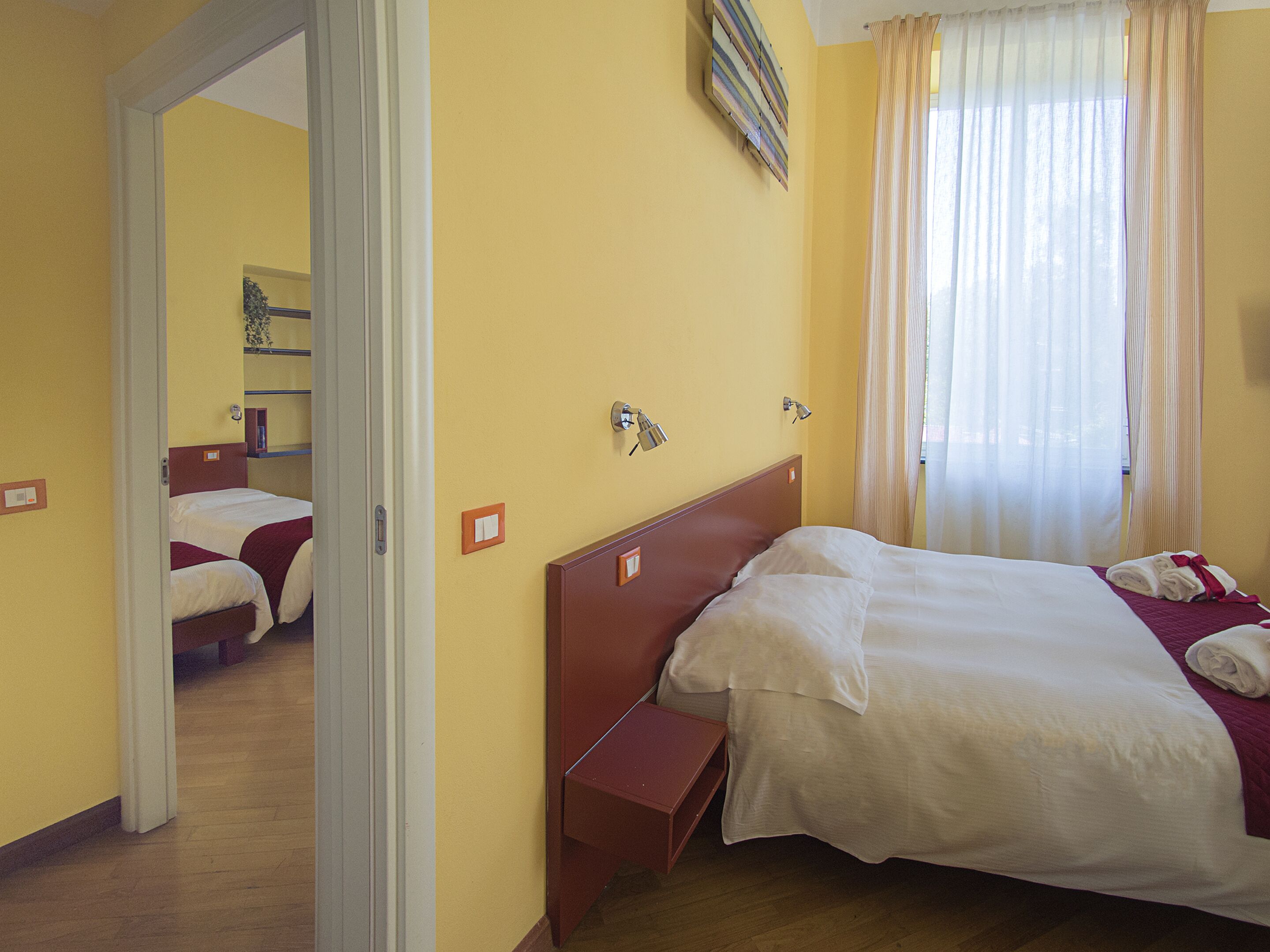 Habitación de hotel con dos camas, cabecero de madera, mesita de noche y espejo.