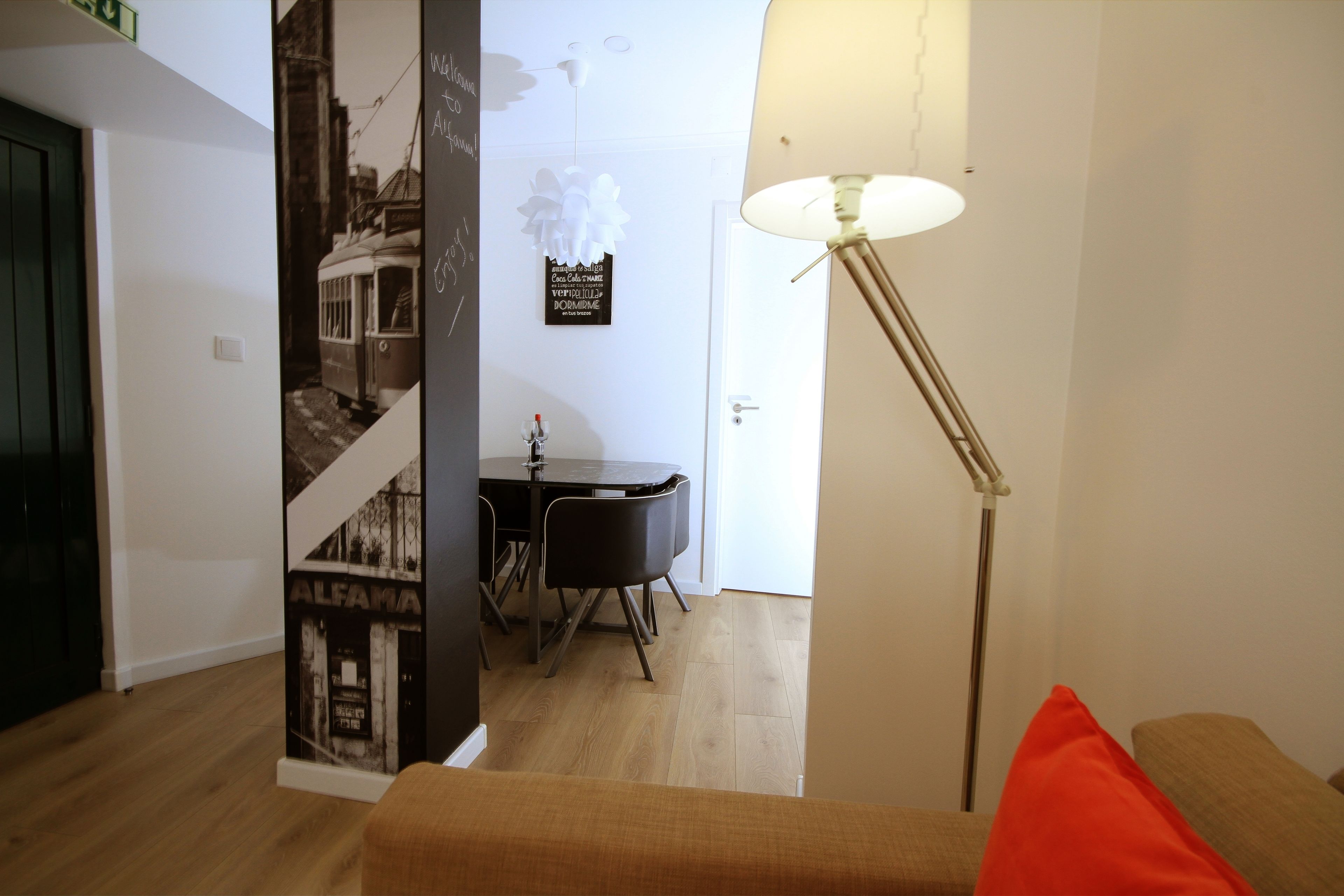 Un interior moderno con comedor, una lámpara y una pared con un cartel antiguo.