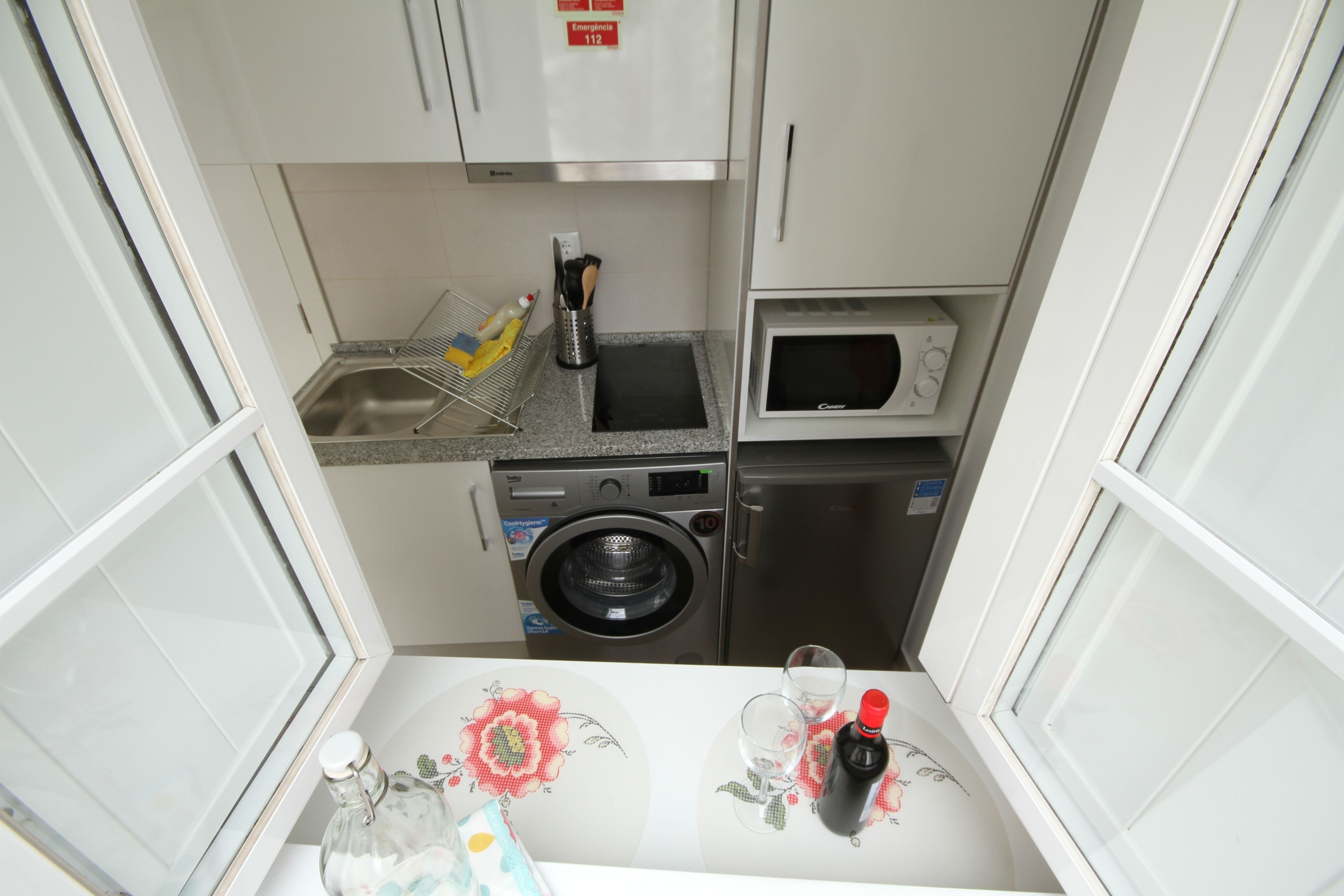 A compact kitchen with a washing machine, microwave, and sink.