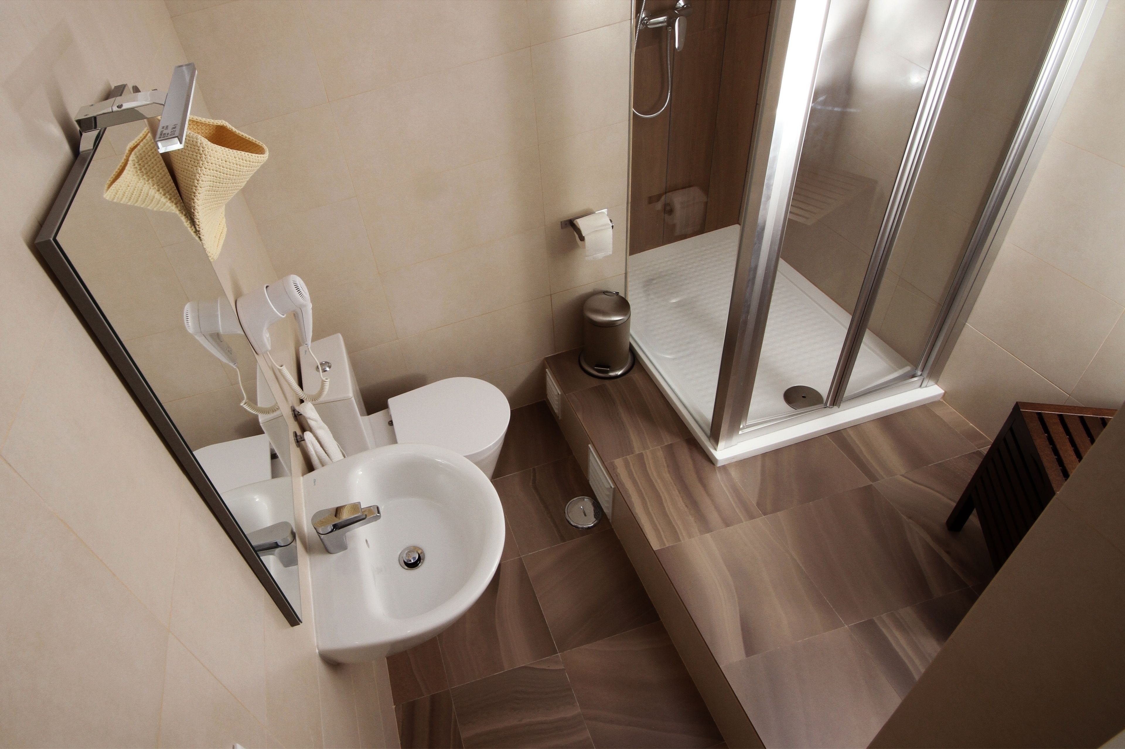 Un bany modern amb un lavabo, vàter i una cabina de dutxa de vidre.