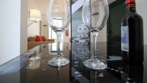 Dos copas de vino vacías sobre una superficie reflectante, con una botella de vino y un cuadro en el fondo.
