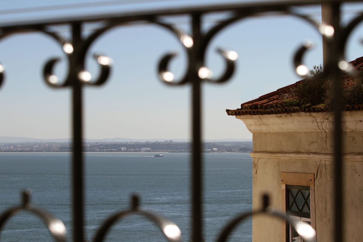 Vista de um corpo d'água, com um horizonte urbano distante e um edifício com telhado de azulejos.