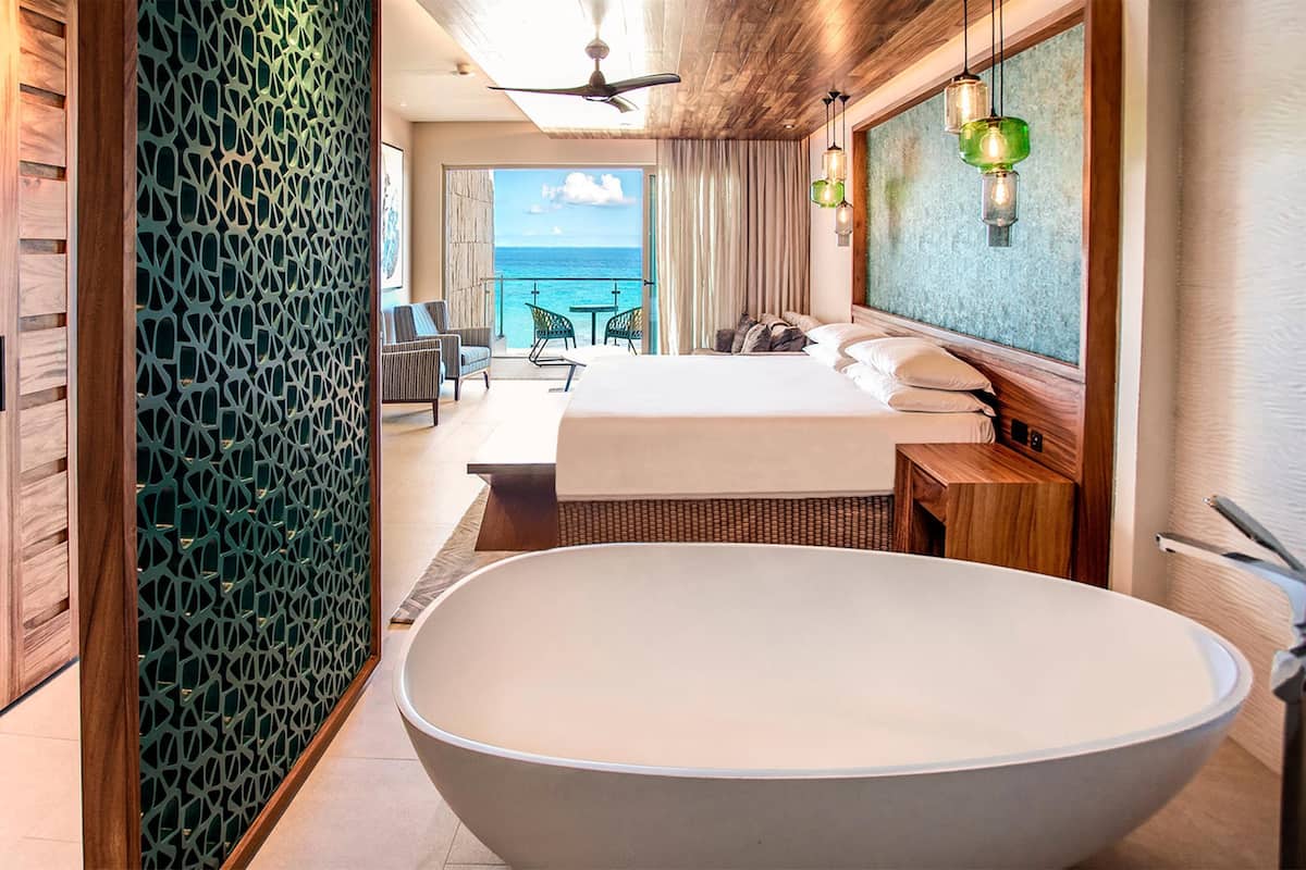 Un hotel moderno con una bañera grande, un balcón con vista al mar y suelo de madera.
