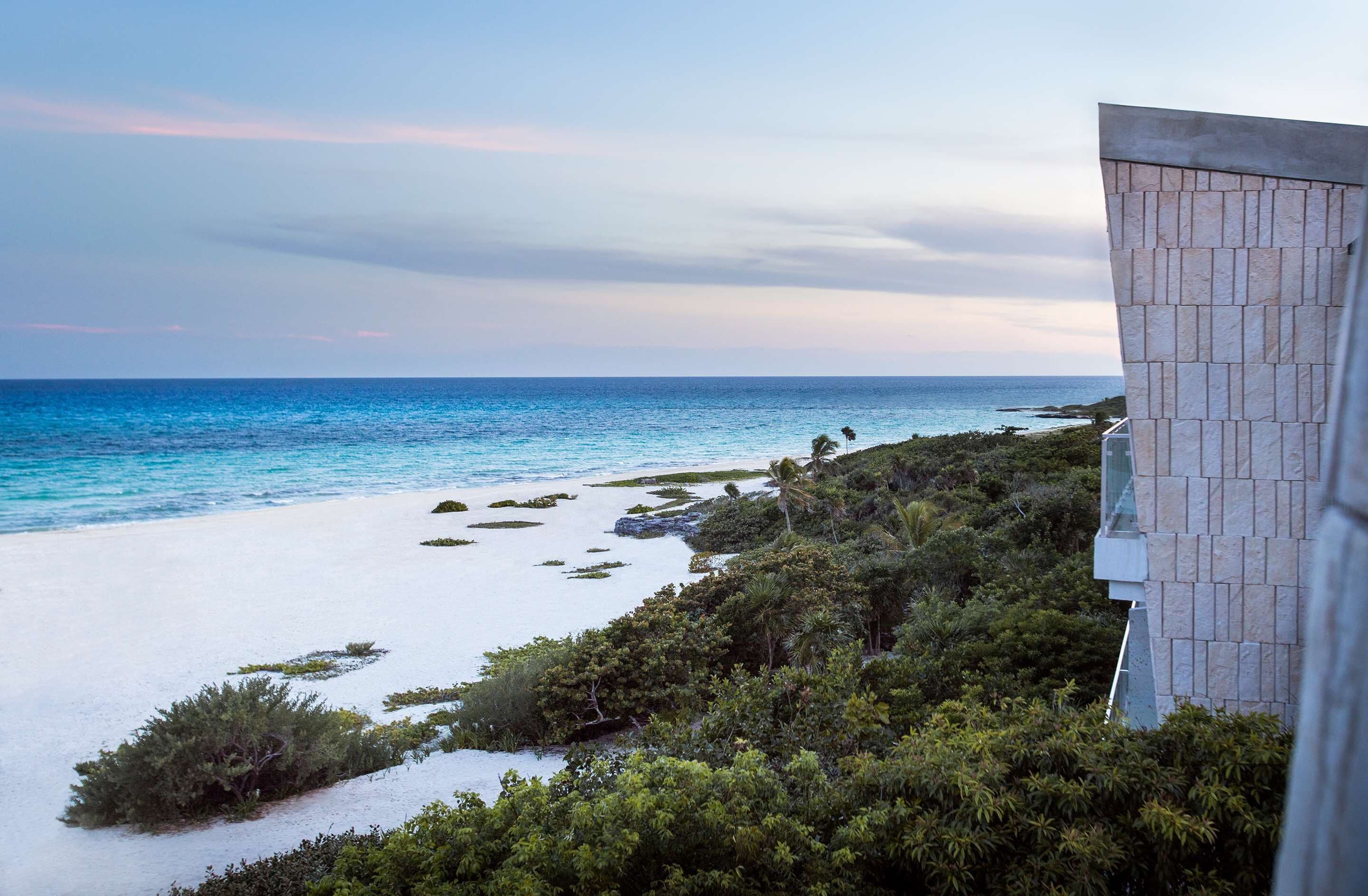 A coastal view with a building featuring a geometric facade.
