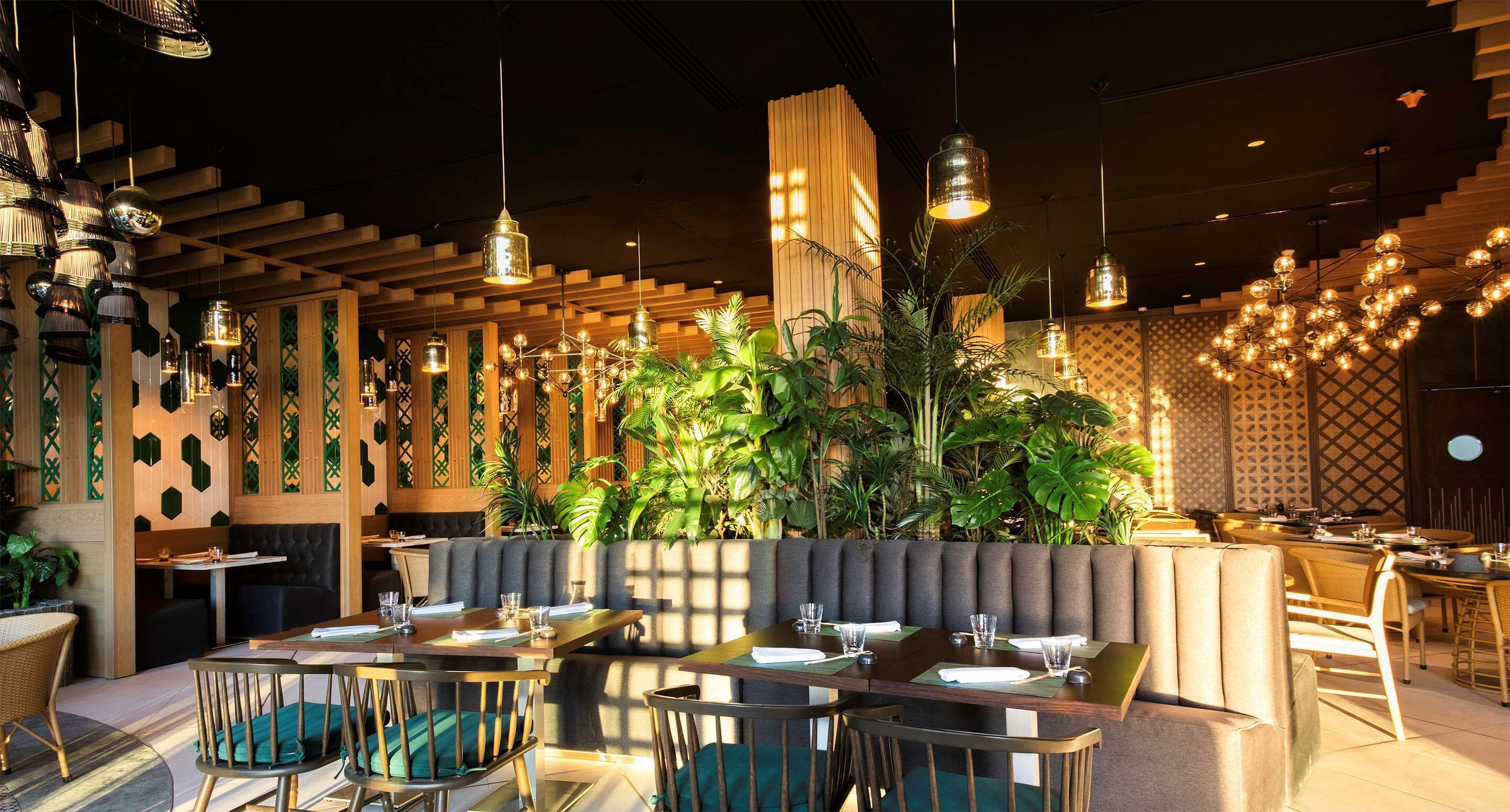 Un restaurant amb diverses sales de menjador, incloent seients a boxes i taules, i una varietat de lluminàries penjants.