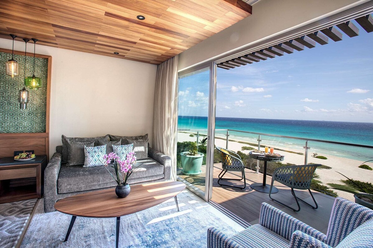 Una habitación moderna con un amplio ventanal corredero que da a un balcón con vistas a la playa.