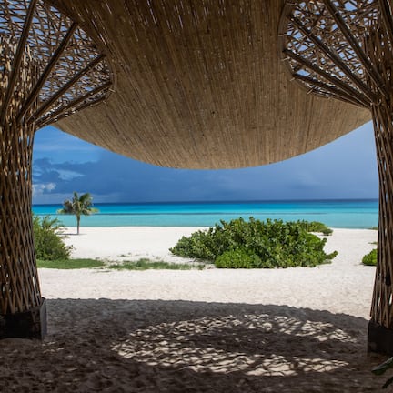A beach view with a thatched canopy structure.