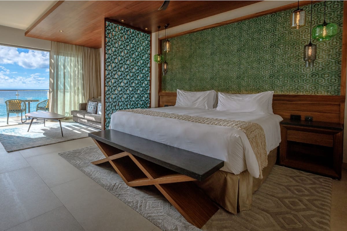 Habitación de hotel con cama, escritorio, silla y vista al mar.